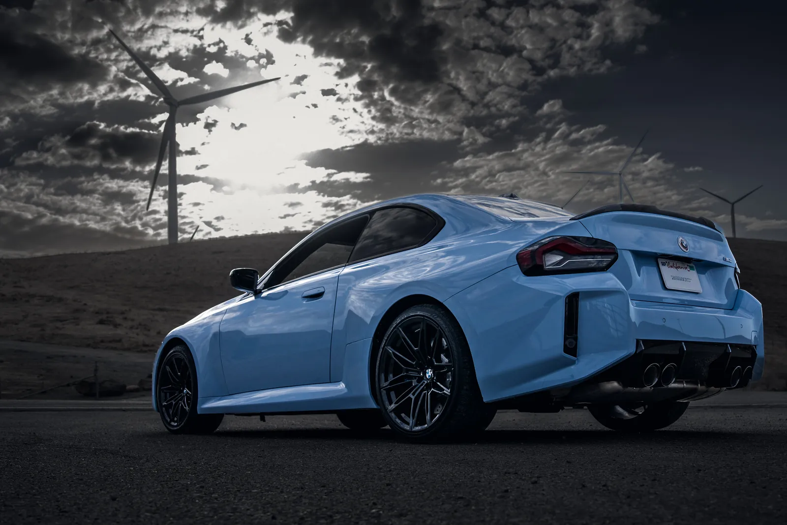 BMW M2 rear three-quarter at a low angle under a dramatic sky