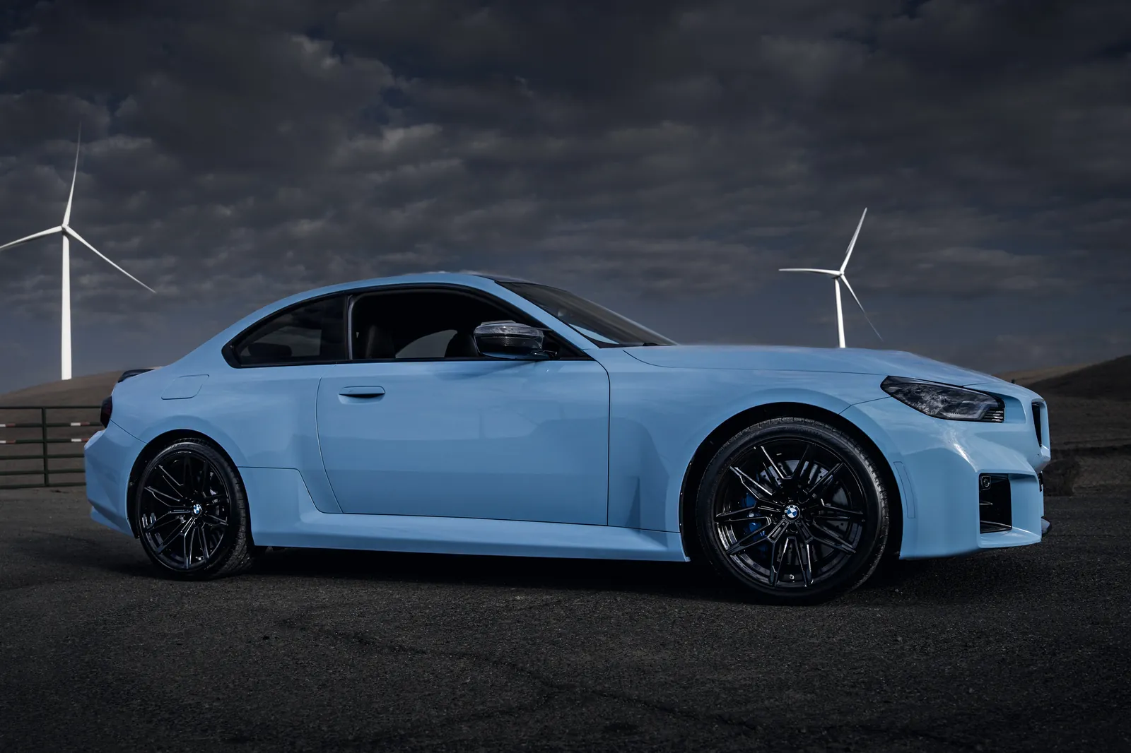 BMW M2 side three-quarter view with wind turbines