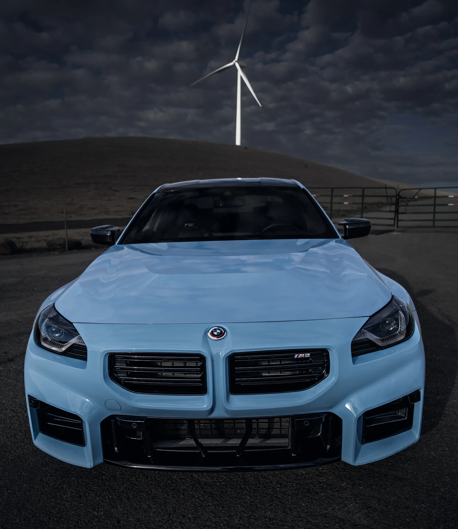 BMW M2 head-on, kidney grille and headlights, wind turbine behind