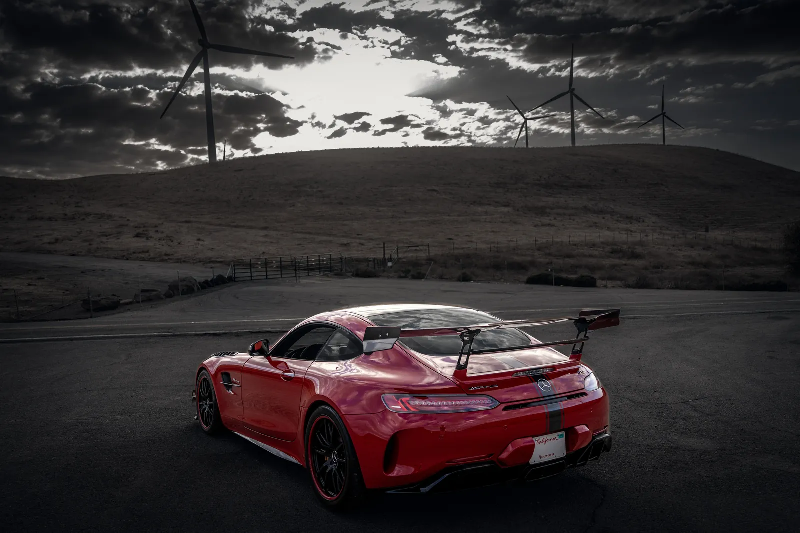 Mercedes-AMG GT R in the distance on an empty lot below wind turbines